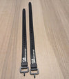 Two black straps with metal buckles on a wooden surface