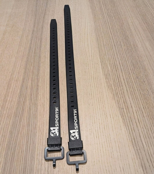 Two black straps with metal buckles on a wooden surface